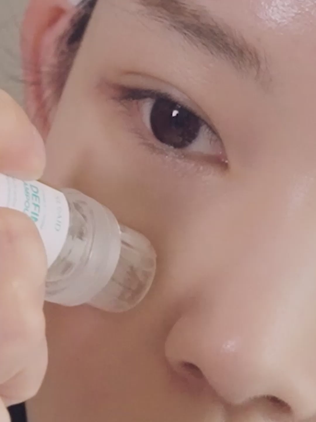 A woman glides a skincare roller applicator across her cheek