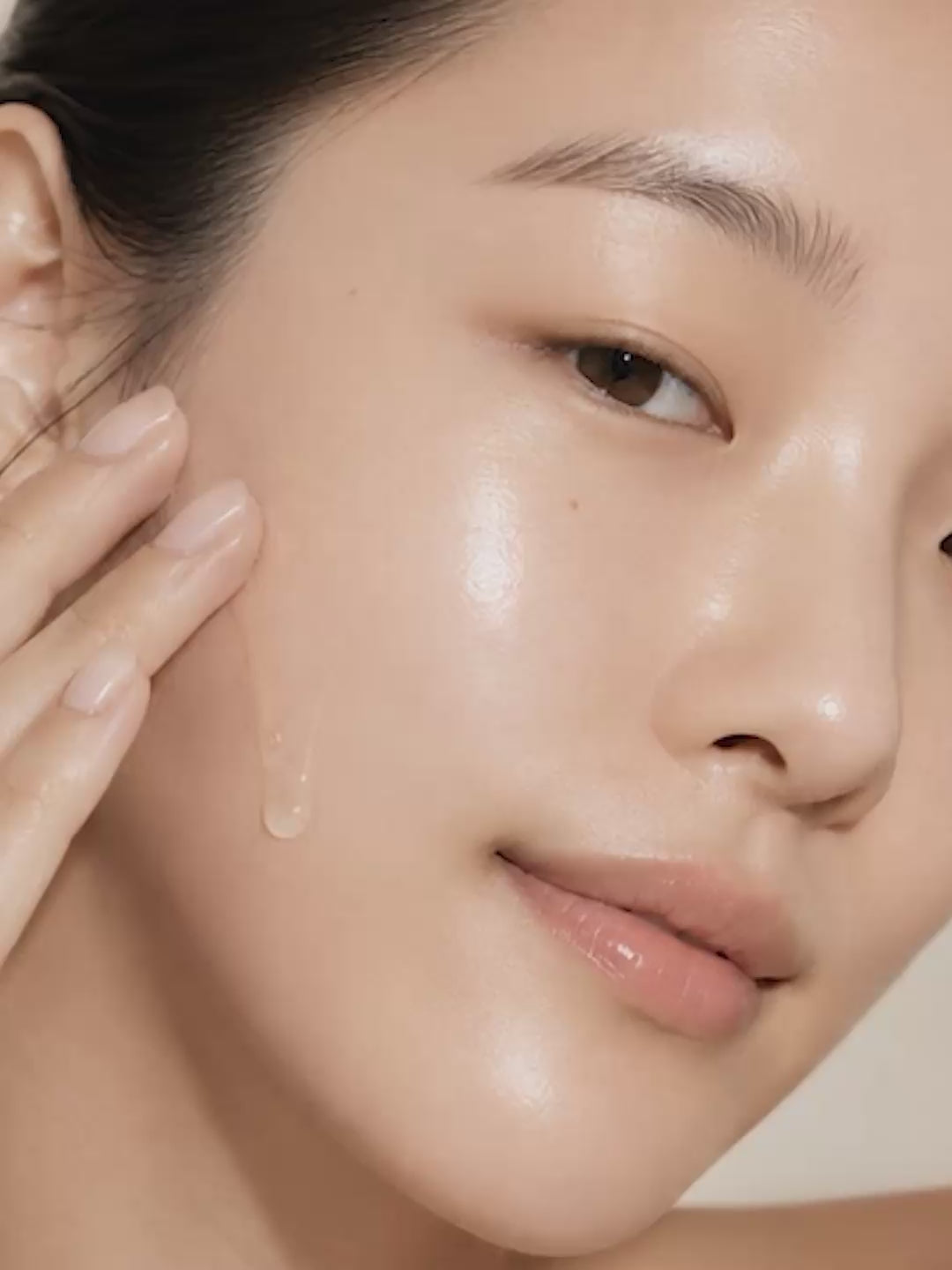 A woman gently massages serum into her cheek with her fingertips