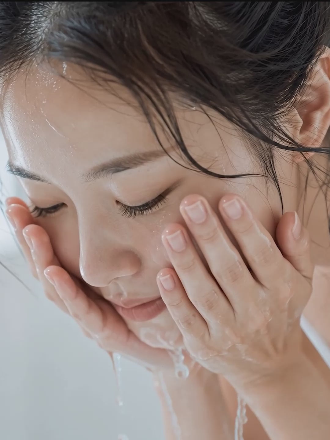A woman gently rinses her face with water during her skincare routine